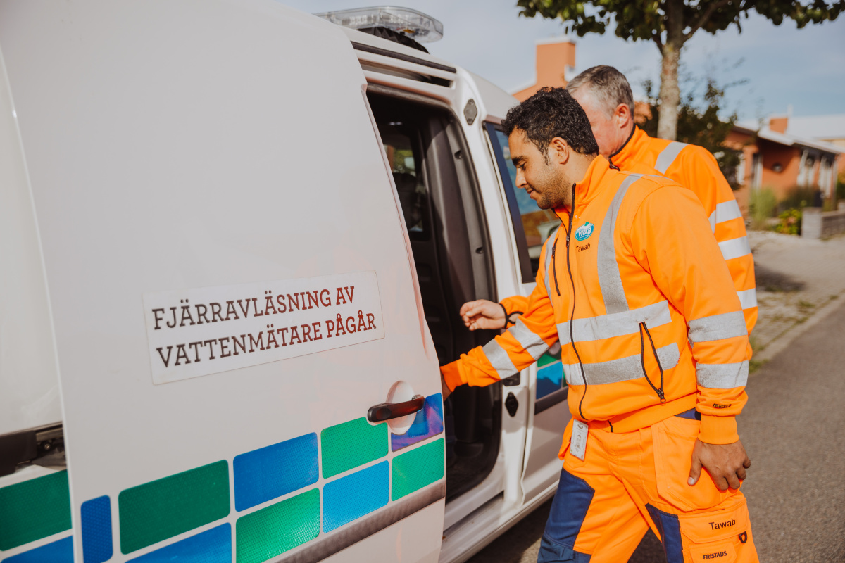 Två vattenmätarinstallatörer vid ett fordon