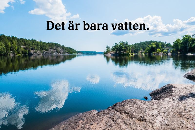 Bild från en klippa ser vi ut över en insjö. Vattnet ligger blankt och molnen speglar sig i vattenytan. Utmed sjöns stränder syns skrovliga klippor och barrskog. Mitt i sjön en liten kobbe med några lövträd.